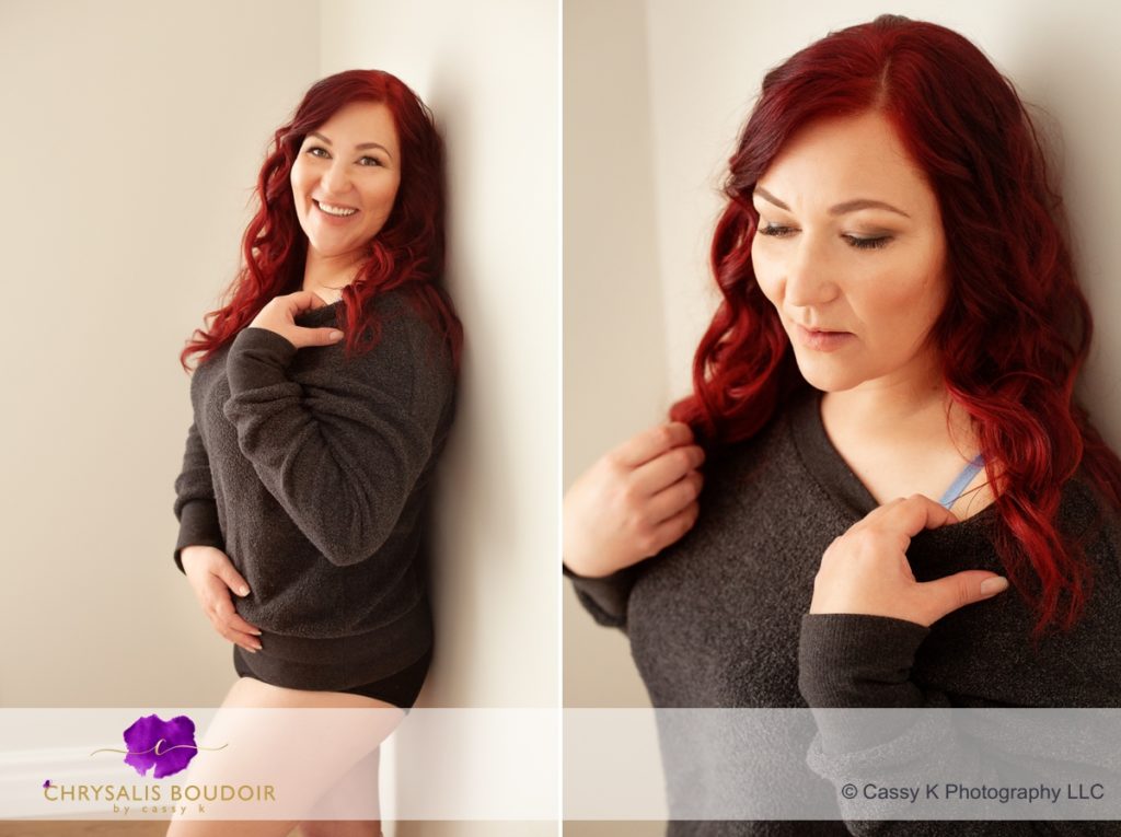 Curly Red Head single mom building confidence wearing grey sweatshirt standing agains wall for Boudoir Photoshoot
