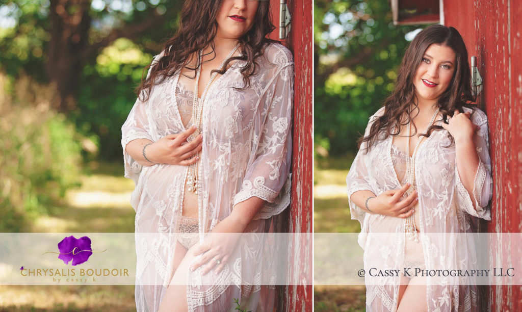 Brunette hair and green eyed woman next to red barn in white lace for outdoor Boudoir Photoshoot