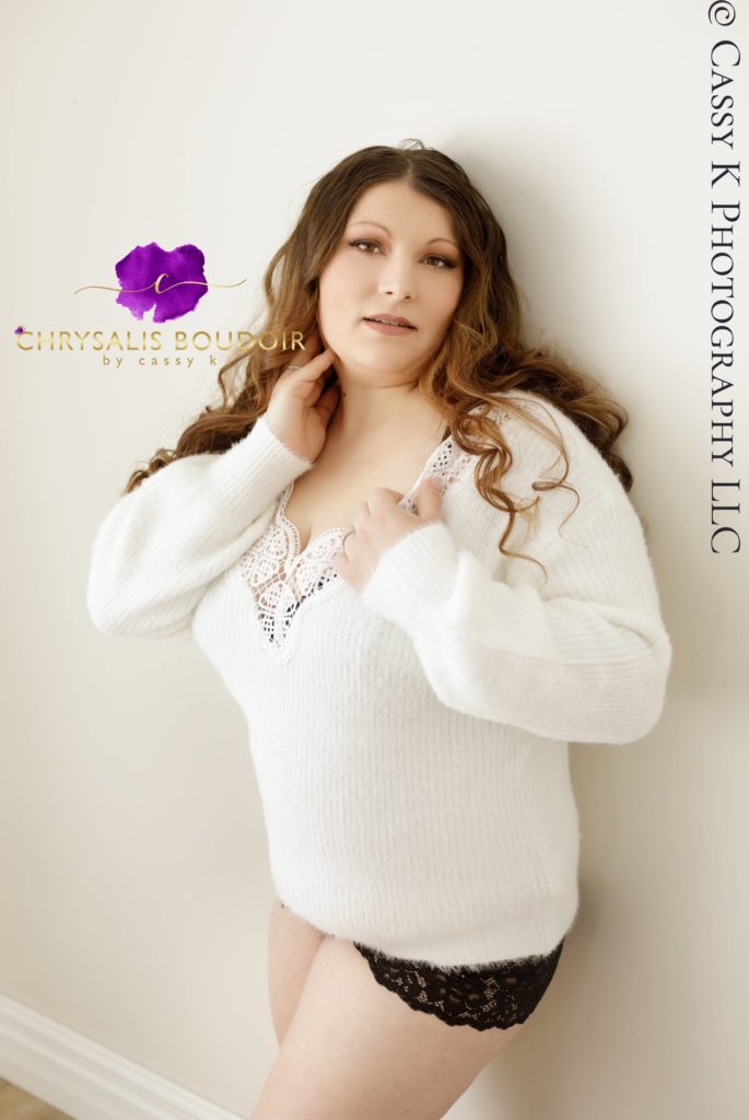 Curly Brunette, brown eyed woman wears white sweater to celebrate her mom bod during Boudoir Photoshoot