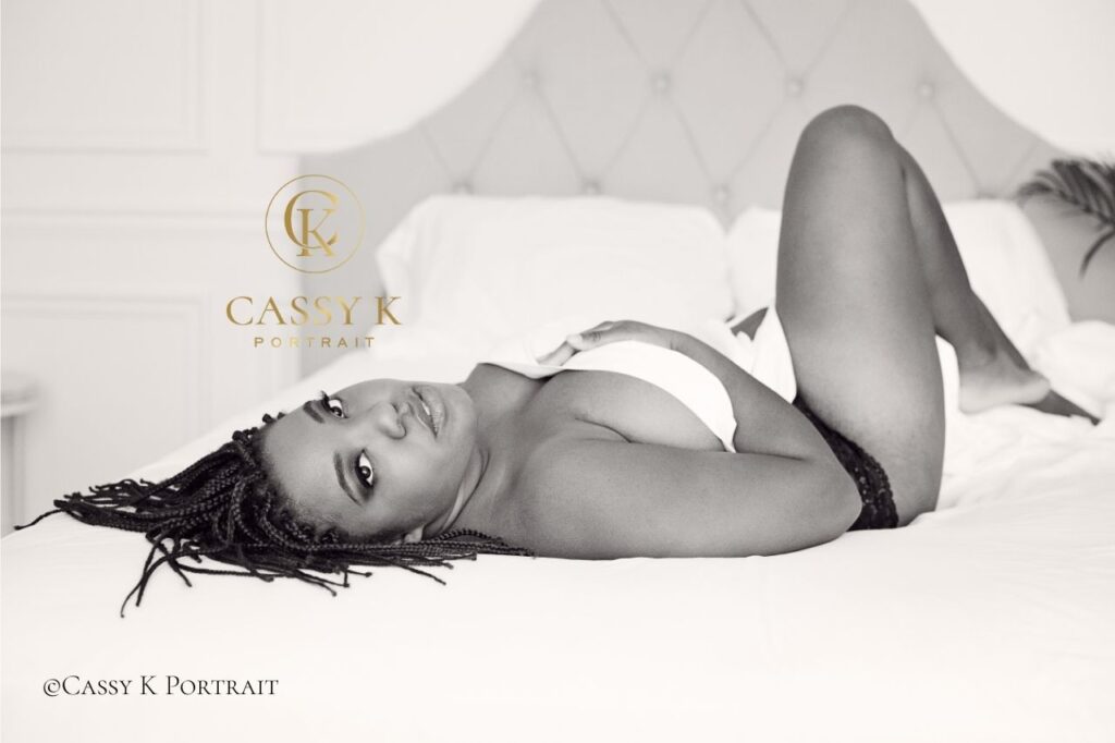 Black woman faces boudoir shoot fears laying on bed looking at the camera