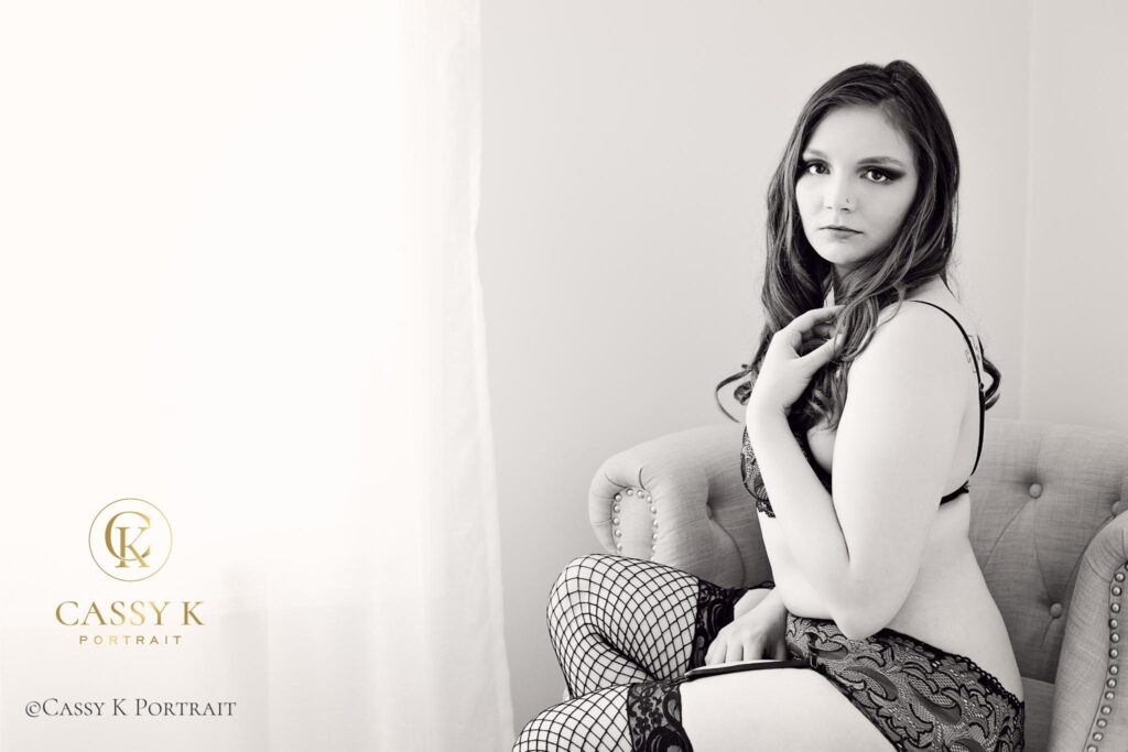 Red haired hazel eyed woman wearing lace lingerie sitting in chair does Black and white boudoir photo shoot for self-love