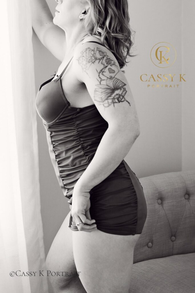 Blond haired blue eyed woman wearing pink slip dress does Black and white boudoir photo shoot for 50th birthday and anniversary