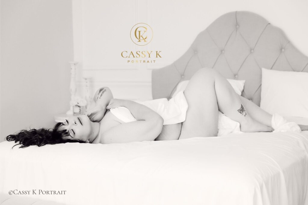 Brunette hair and green eyed woman investing in self love during white sheet Boudoir Photoshoot