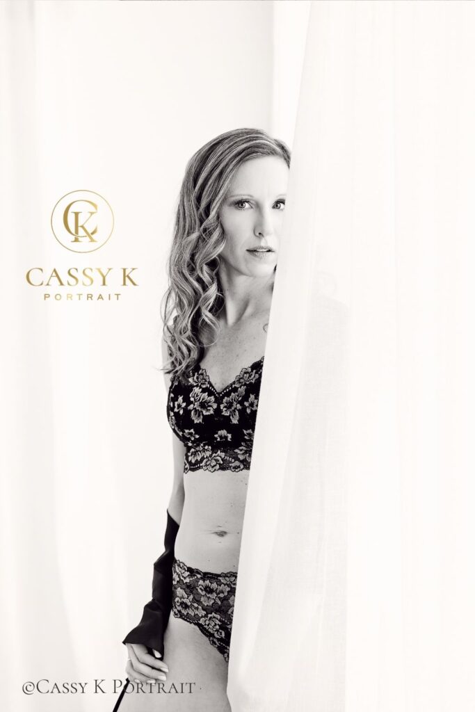 Blond hair mother wearing black lace booked a window light Boudoir Photoshoot to Escape and gain confidence