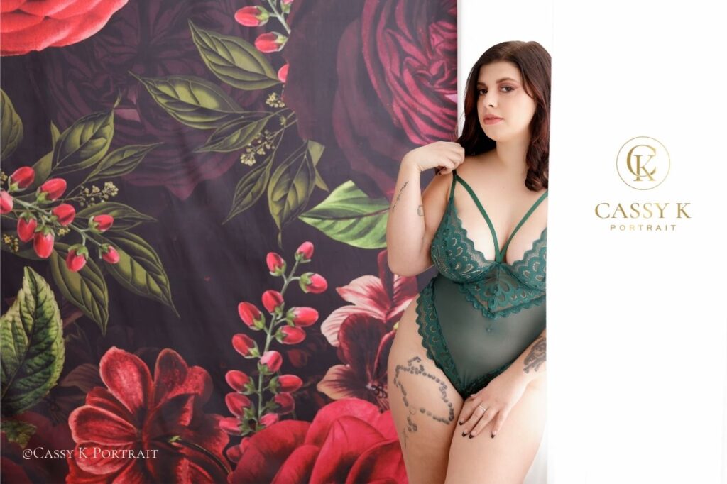 Young woman wearing forest green teddy bodysuit works through body changes and falls in love with herself for the first time during boudoir photo shoot