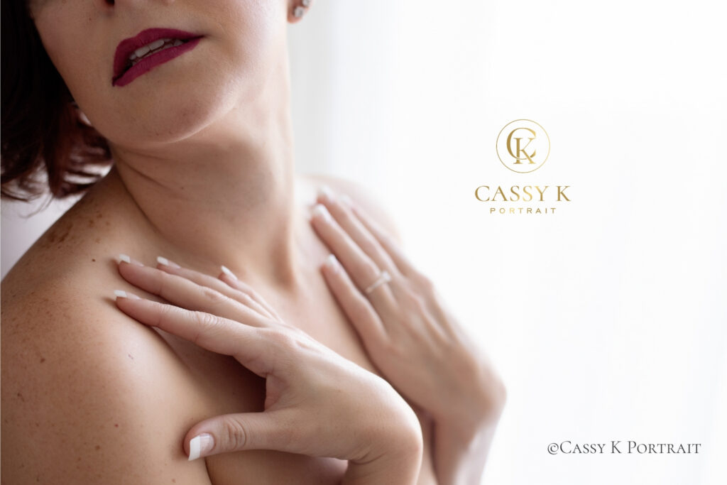Close-up beauty portrait of a woman with her hands resting softly across her collarbone.