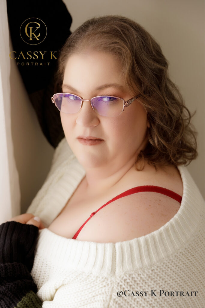 Close-up portrait of a woman wearing glasses and an oversized white-and-black sweater.