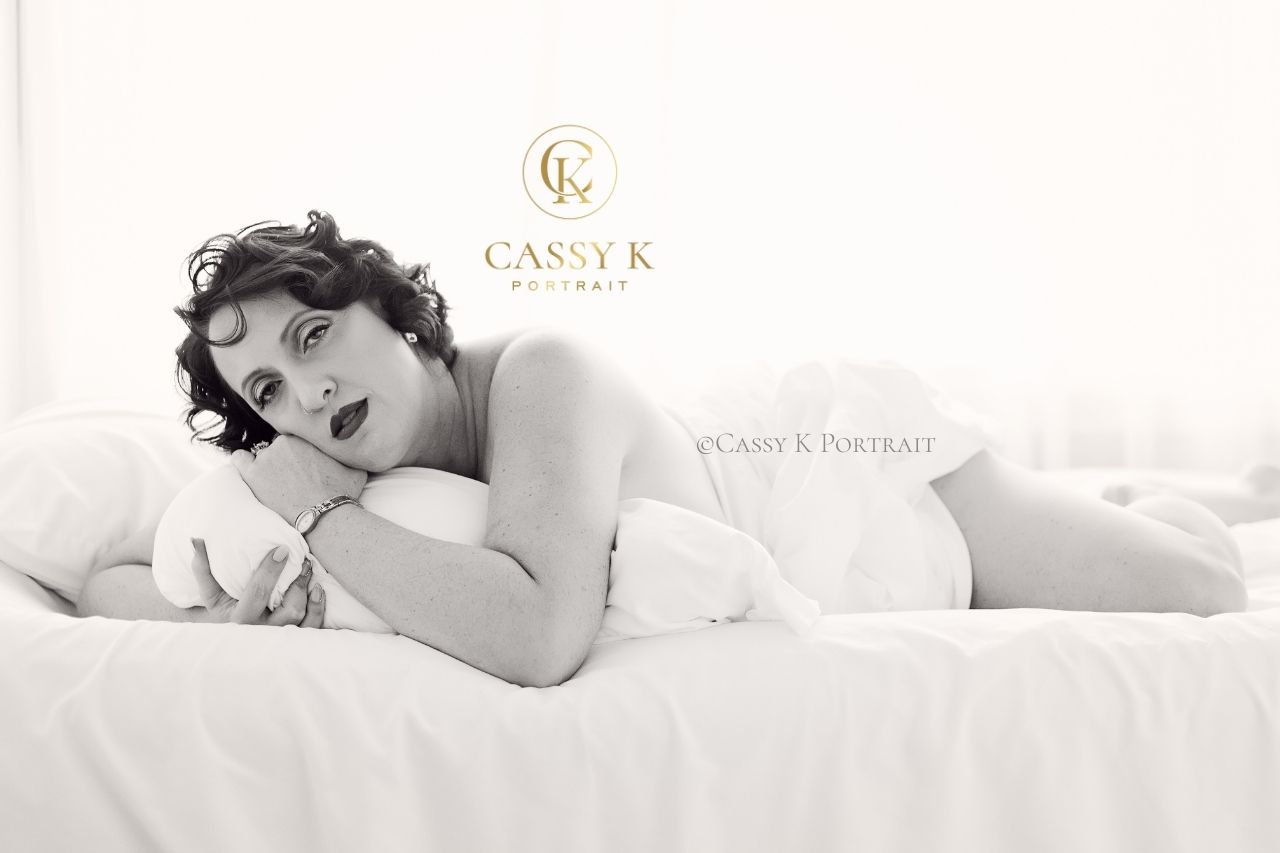 Brunette Blue eyed woman laying on bed with body confidence boudoir photography