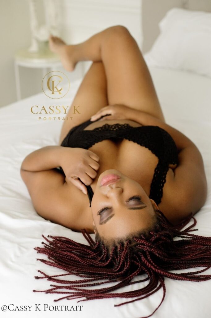 Black woman faces boudoir shoot fears laying on bed in black bra