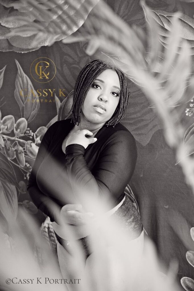 Black woman faces boudoir shoot fears surrounded in plants in sheer black top and panties