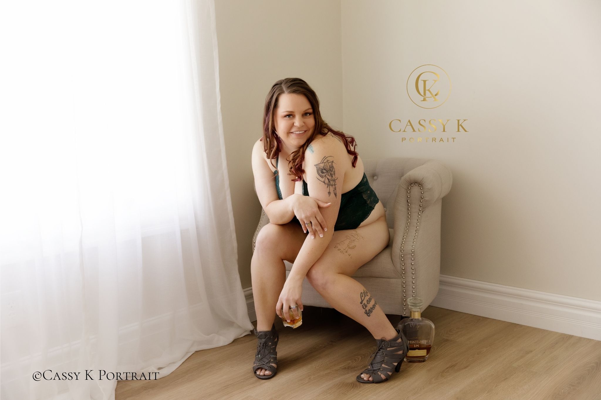 Burgundy Blond hair and blue eyed woman laughing playfully during empowering boudoir photoshoot with whistlepig whiskey