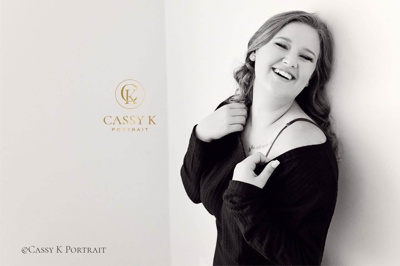 Busy mom wearing black sweater laughs during boudoir photo shoot experience