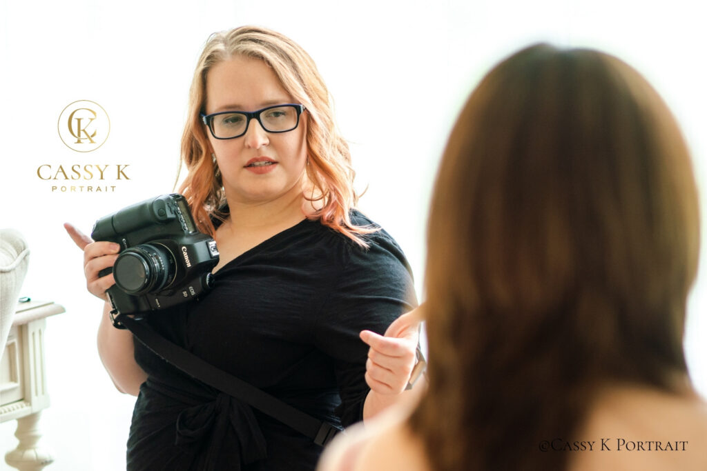 Portrait photographer holding her camera and giving direction to a client during a fully guided session.
